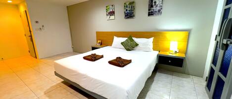 Una habitación de hotel con una cama, una mesita de noche, una lámpara y una puerta.