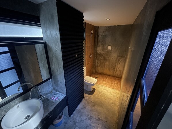 Un baño con lavamanos, espejo y zona de ducha.