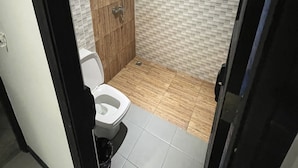 A bathroom with a toilet, shower, and tiled floor. - Cocoon Islanda Hotel (Patong)