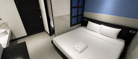 A hotel room with a bed, a desk, and a bathroom.