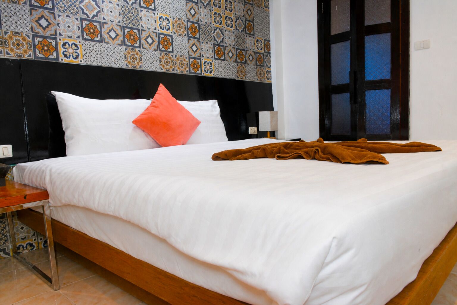 Una habitación de hotel con cama, mesita de noche, ventana y vista, y pared con diseño.