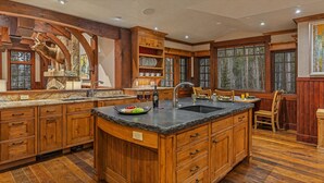 Une cuisine spacieuse dotée de meubles en bois, de plans de travail en granit et d’un grand îlot central avec un évier.