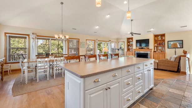A spacious kitchen with a large island, wooden cabinets, and a dining area with chairs.