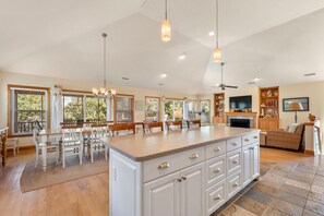 Una cocina amplia con una isla grande, armarios de madera y un comedor con sillas.