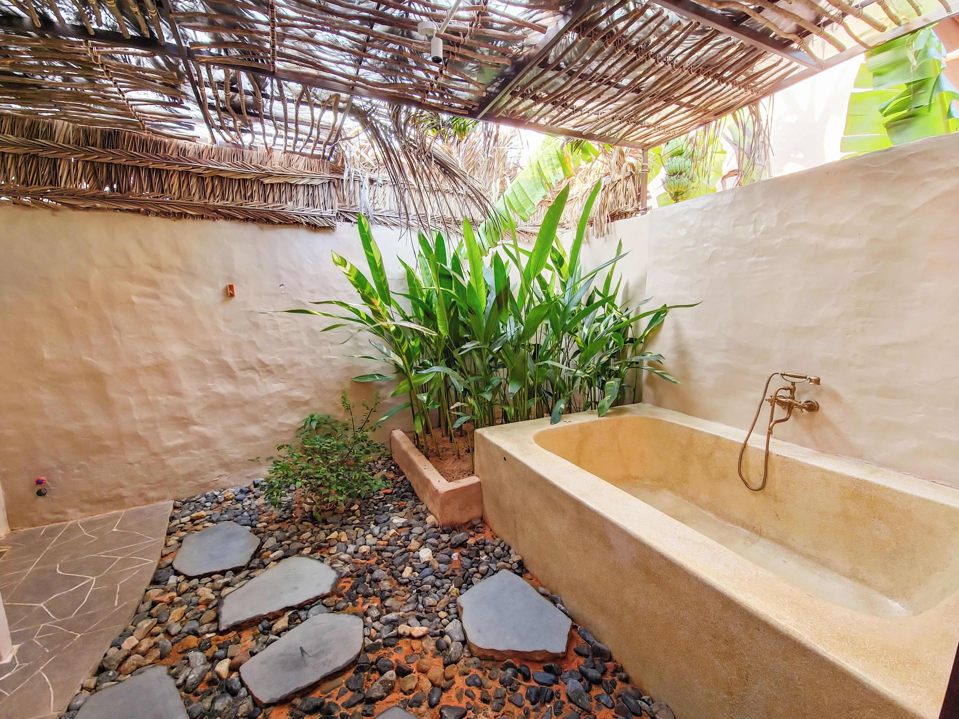 A bathroom with a bathtub, a small garden area with plants, and a stone pathway.