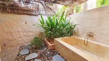 A bathroom with a bathtub, a small garden area with plants, and a stone pathway.