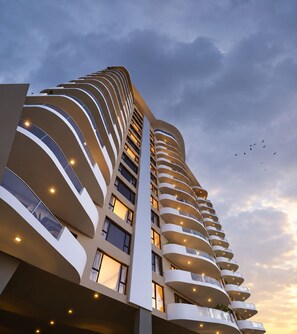 A high-rise building with multiple balconies and a curved facade. - Capital M Apartments by YourHost (Nairobi)