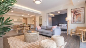 Uma sala de estar moderna com sofá, pufes e um espaço de jantar com mesa e cadeiras.
