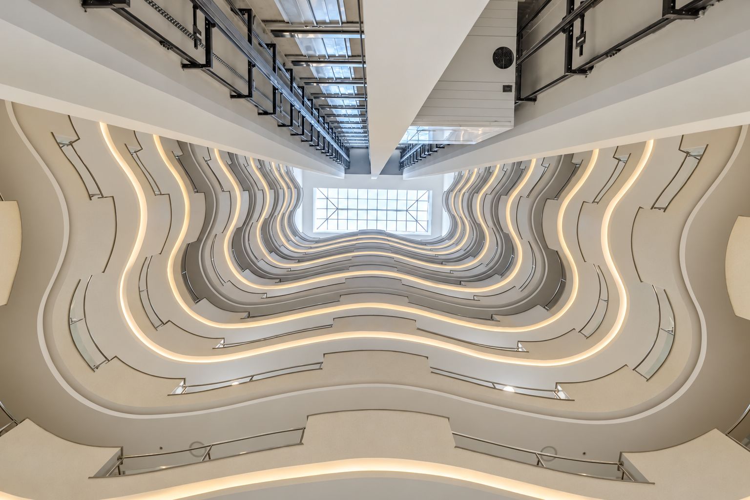 Interior moderno com uma escadaria espiral central e um claraboia.