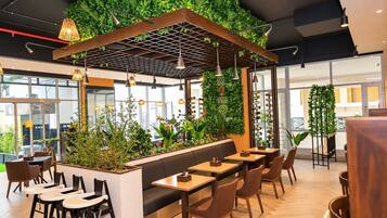 En moderne restaurant med en grøn væg, træborde og stole.