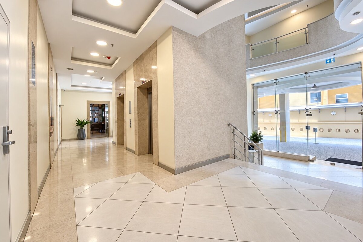 Un moderno vestíbulo de hotel con un espacio amplio, una recepción y una escalera que conduce a un piso superior.