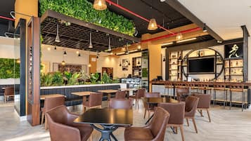 A modern restaurant interior with a bar area, seating arrangements, and a green wall with plants.