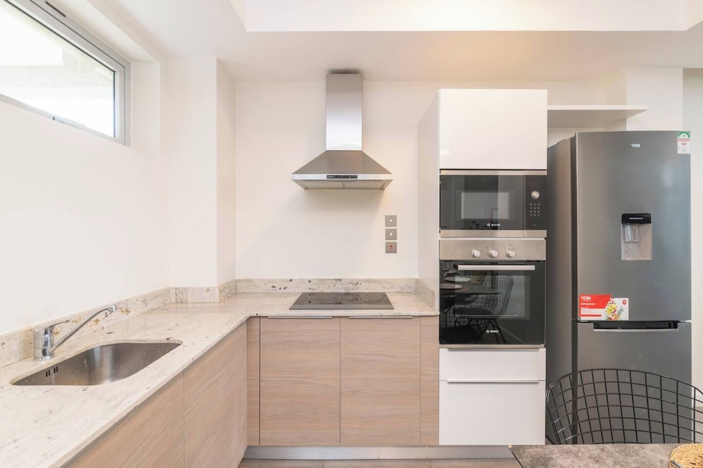 Cozinha moderna com geladeira de aço inoxidável, forno embutido, micro-ondas e fogão a gás.