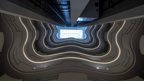 Interior moderno com arquitetura elegante, um claraboia central e linhas curvas nas paredes.