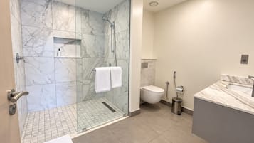 Une salle de bain moderne avec une douche à parois de verre, des toilettes et un lavabo doté d’un plan de travail en marbre.