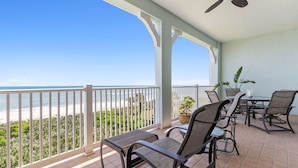Un balcone con vista sulla spiaggia, arredi da esterno e una ventola a soffitto.