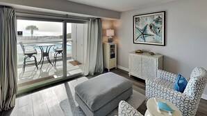 Una habitación de hotel moderna con balcón, un ventanal grande, un sofá, un armario y un cuadro.