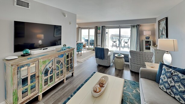 Un salón amplio con una televisión de pantalla plana grande, un mueble de madera, un sofá y un comedor con sillas y una mesa.