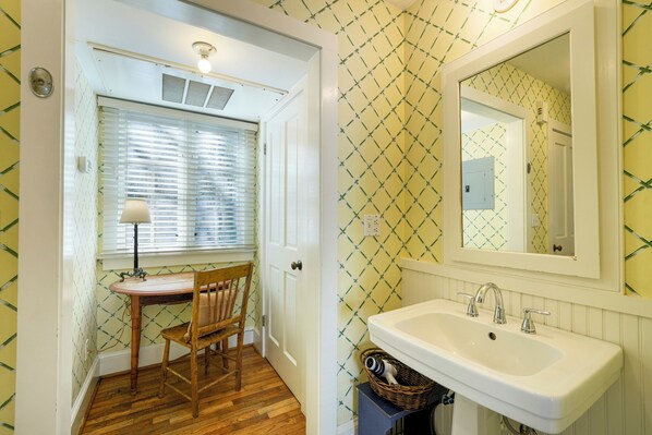 A bathroom with a sink, mirror, and window with blinds.