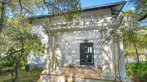 A white building with a porch supported by columns, a door with glass panels, and steps leading up to the porch. - Home w/ Prime Location 4 Mins to Beach in Seaside, Porch + 2 Adult Bikes (Santa Rosa Beach)
