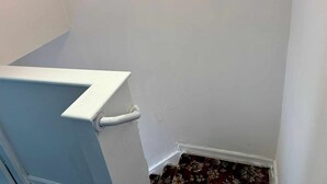 Una esquina de una habitación con paredes blancas y una puerta con picaporte blanco.