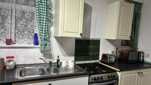 Una cocina compacta con lavabo, estufa y armarios.