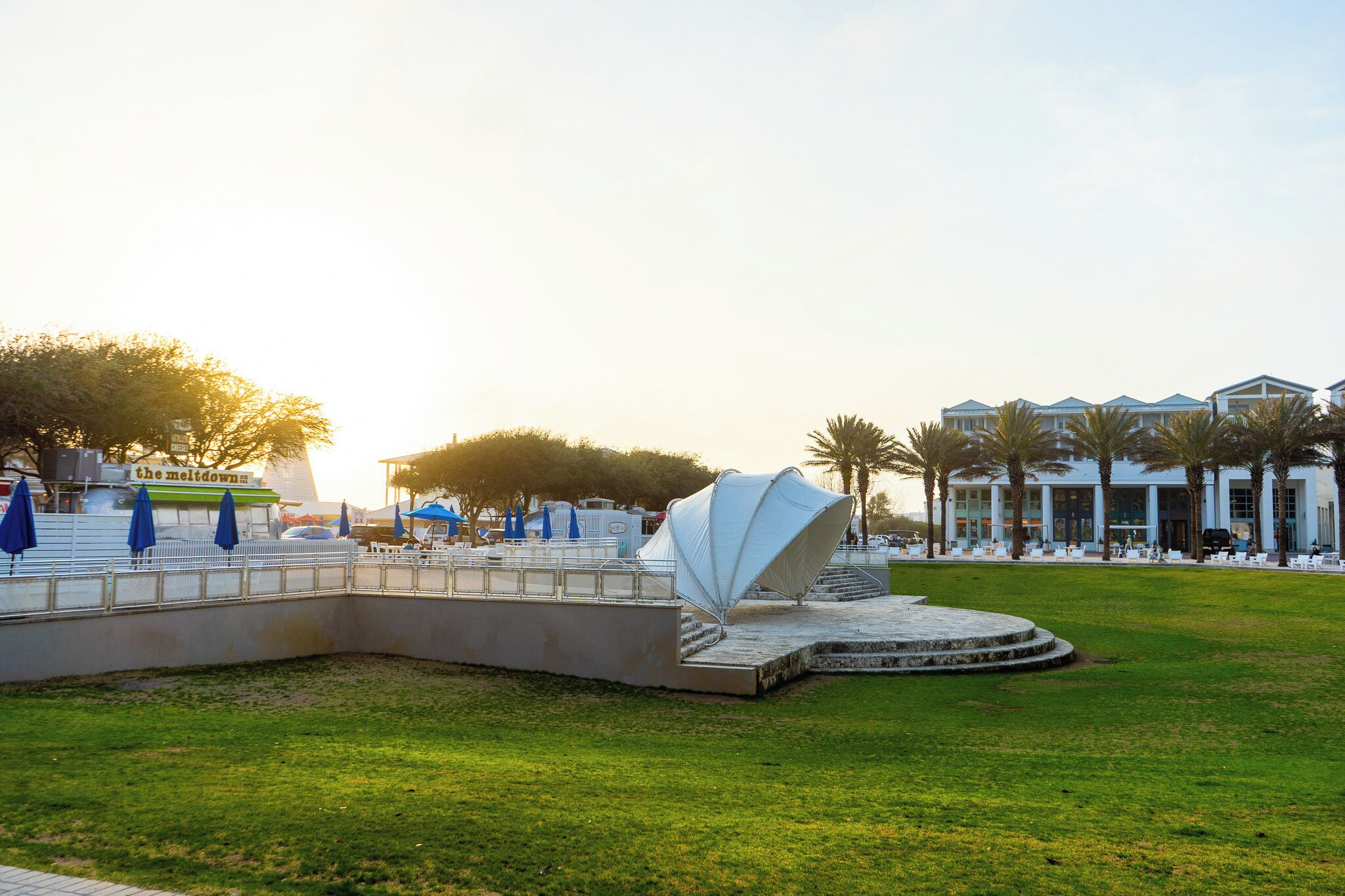 Een modern hotel met een zwembad, terras en een opvallende witte parasolstructuur.