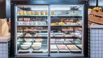 Un présentoir réfrigéré contenant divers produits alimentaires, notamment des yaourts, des salades de fruits et de la charcuterie.