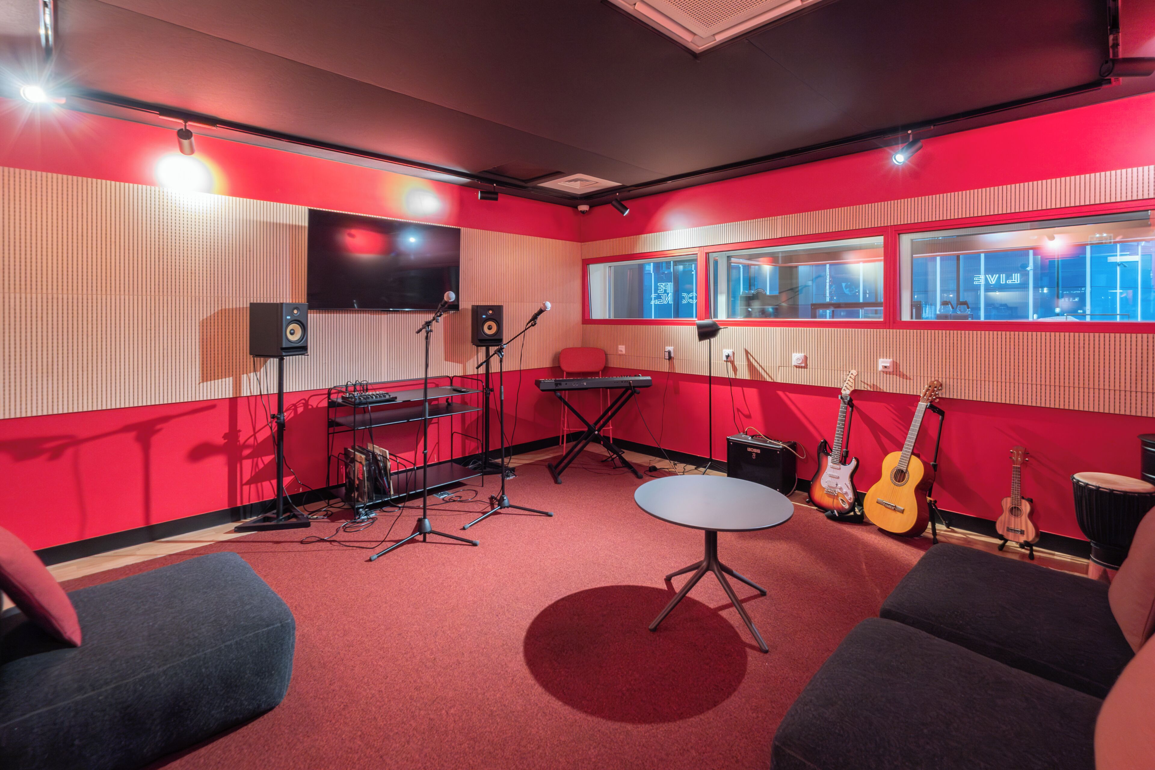 A recording studio with soundproofing, a mixing console, microphones, speakers, and musical instruments.