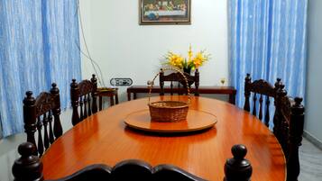 A dining table with a basket and flowers, surrounded by wooden chairs.