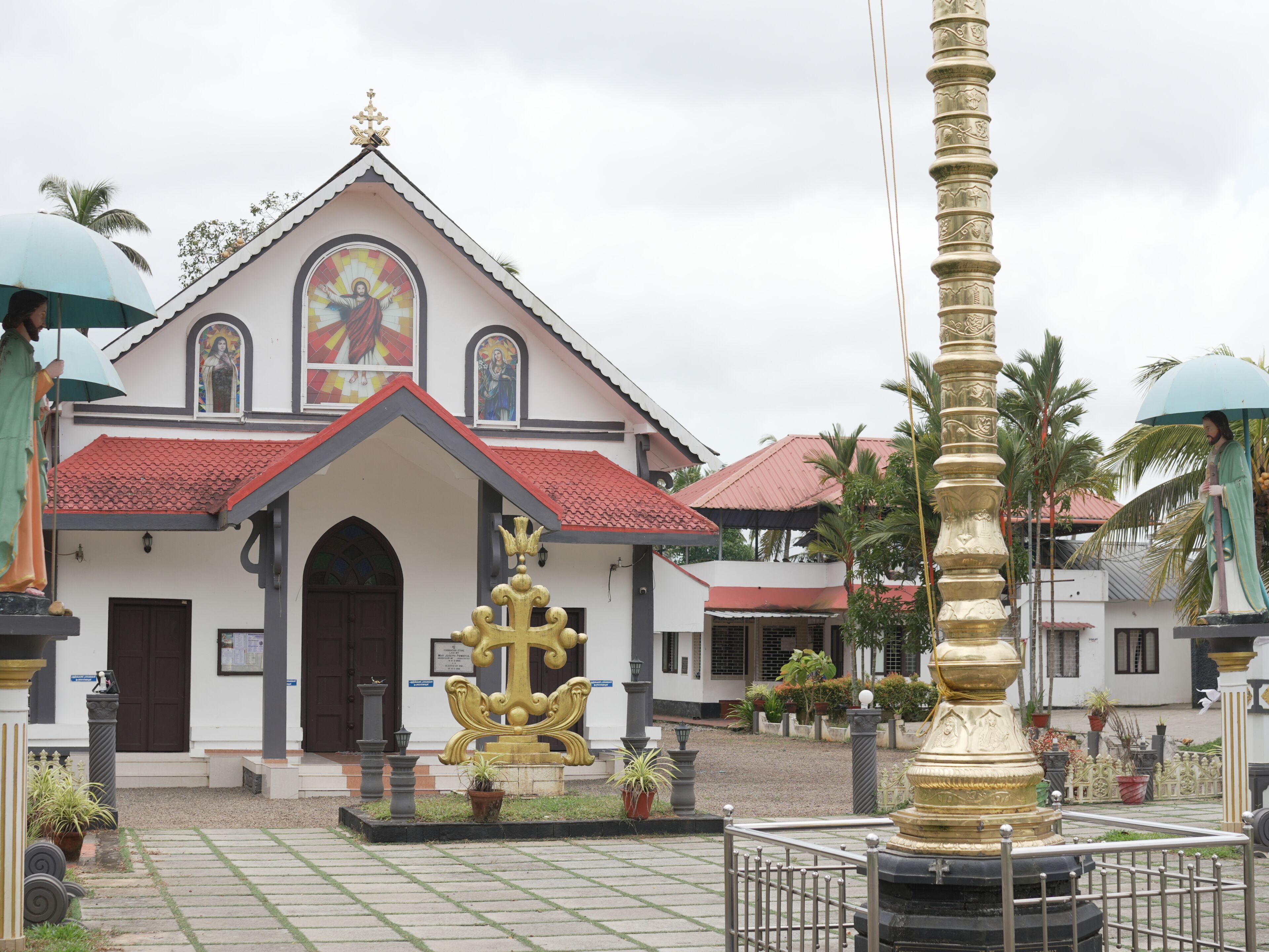A church with a red-tiled roof, a central golden statue, and a white facade.