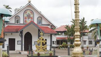 A church with a red-tiled roof, a central golden statue, and a white facade.