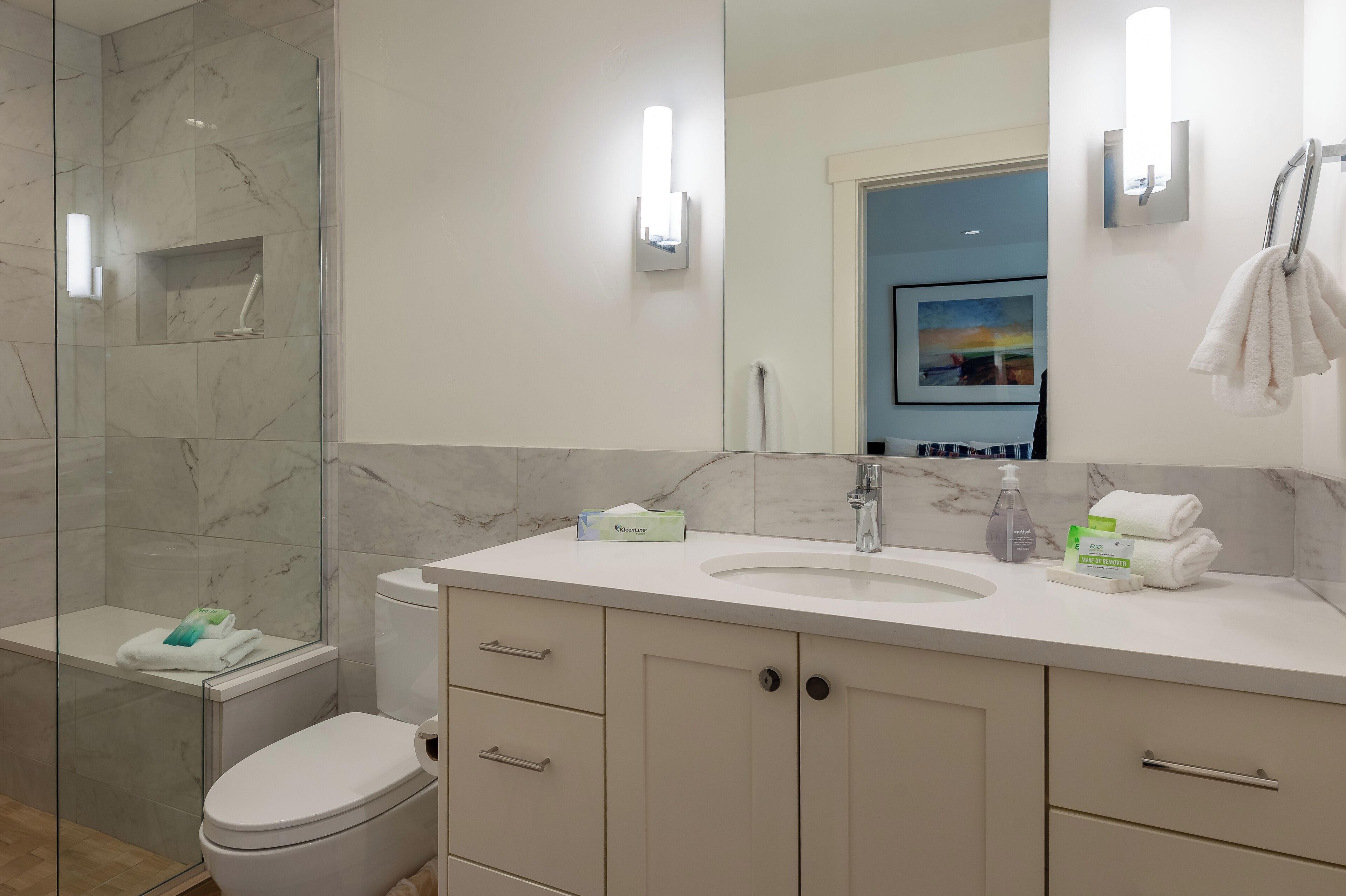 Un baño moderno con ducha de vidrio, lavamanos blanco y retrete.