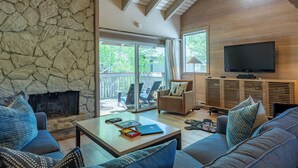 Un salon chaleureux avec une cheminée en pierre, un téléviseur et des fauteuils confortables.