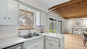 A modern kitchen with white cabinets, a Bosch dishwasher, a sink, and a window. - 3BR Gem in Allandale (Austin)