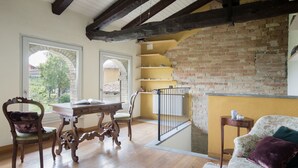 Une pièce avec une table en bois, des chaises, un canapé et un mur en briques.