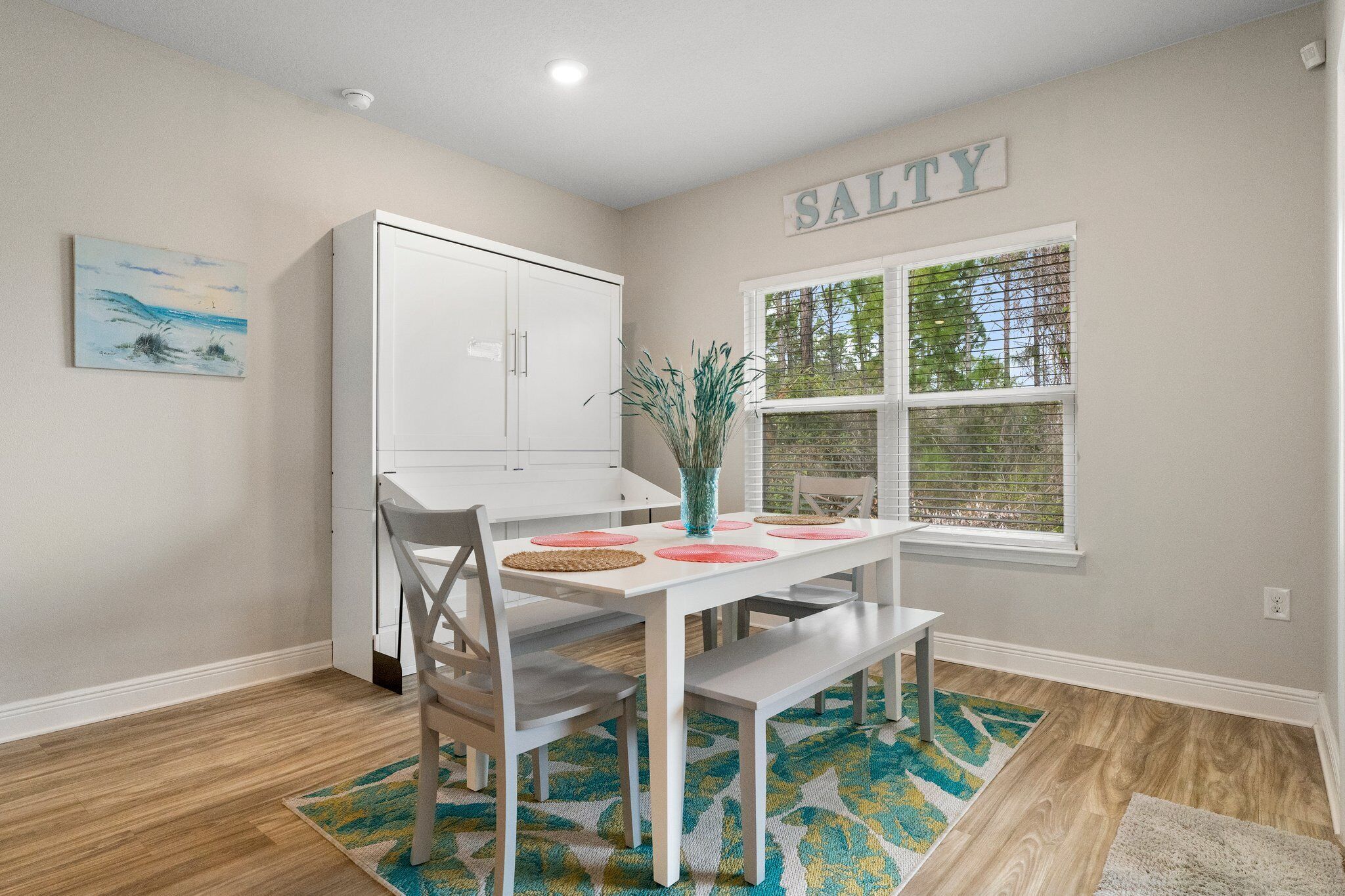 A dining area with a white table, chairs, and a window with blinds.