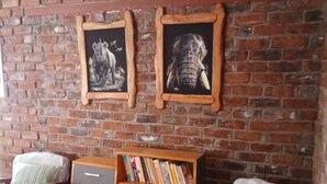 Un coin salon accueillant avec deux chaises en bois et une bibliothèque adossée à un mur de briques.