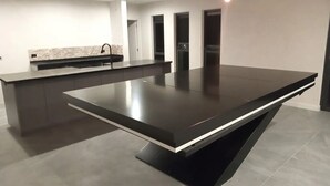 Une cuisine moderne dotée d’un grand îlot central, d’un four encastré et d’un plan de travail en granit.