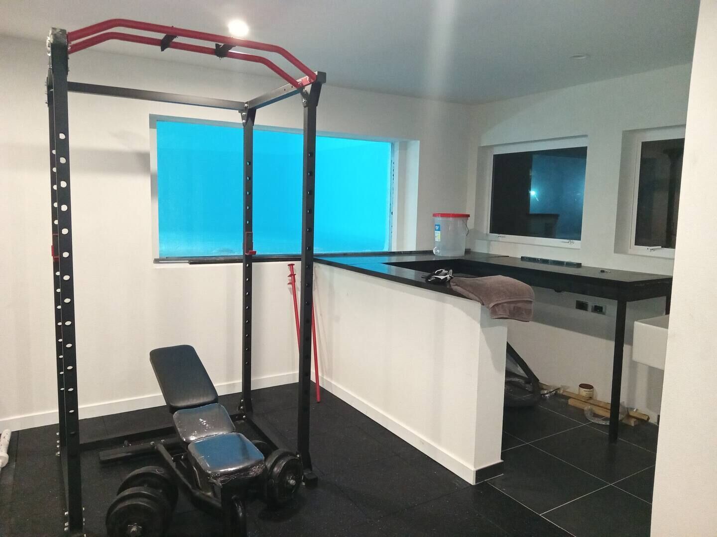 Ein Heimfitnessraum mit Klimmzugstange, Bank und Gewichten.