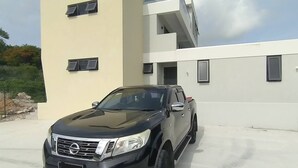 Un VUS noir était garé devant un bâtiment moderne à deux étages, doté d’un toit plat et de grandes fenêtres.