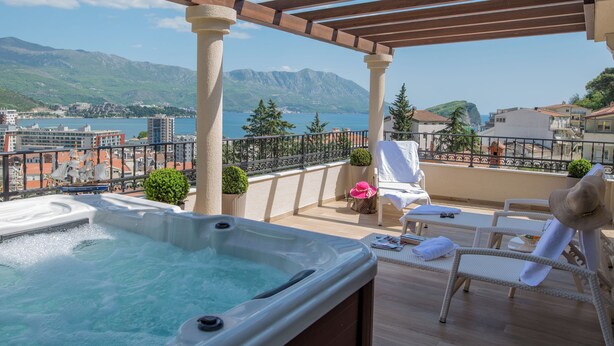 A rooftop terrace with a hot tub, lounge chairs, and a view of the sea and mountains. - Villa Danigo (Budva)