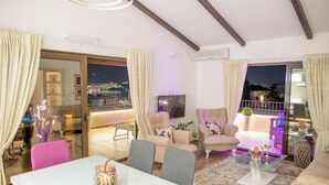 A modern living room with a glass dining table, two sofas, and a TV. - Villa Danigo (Budva)