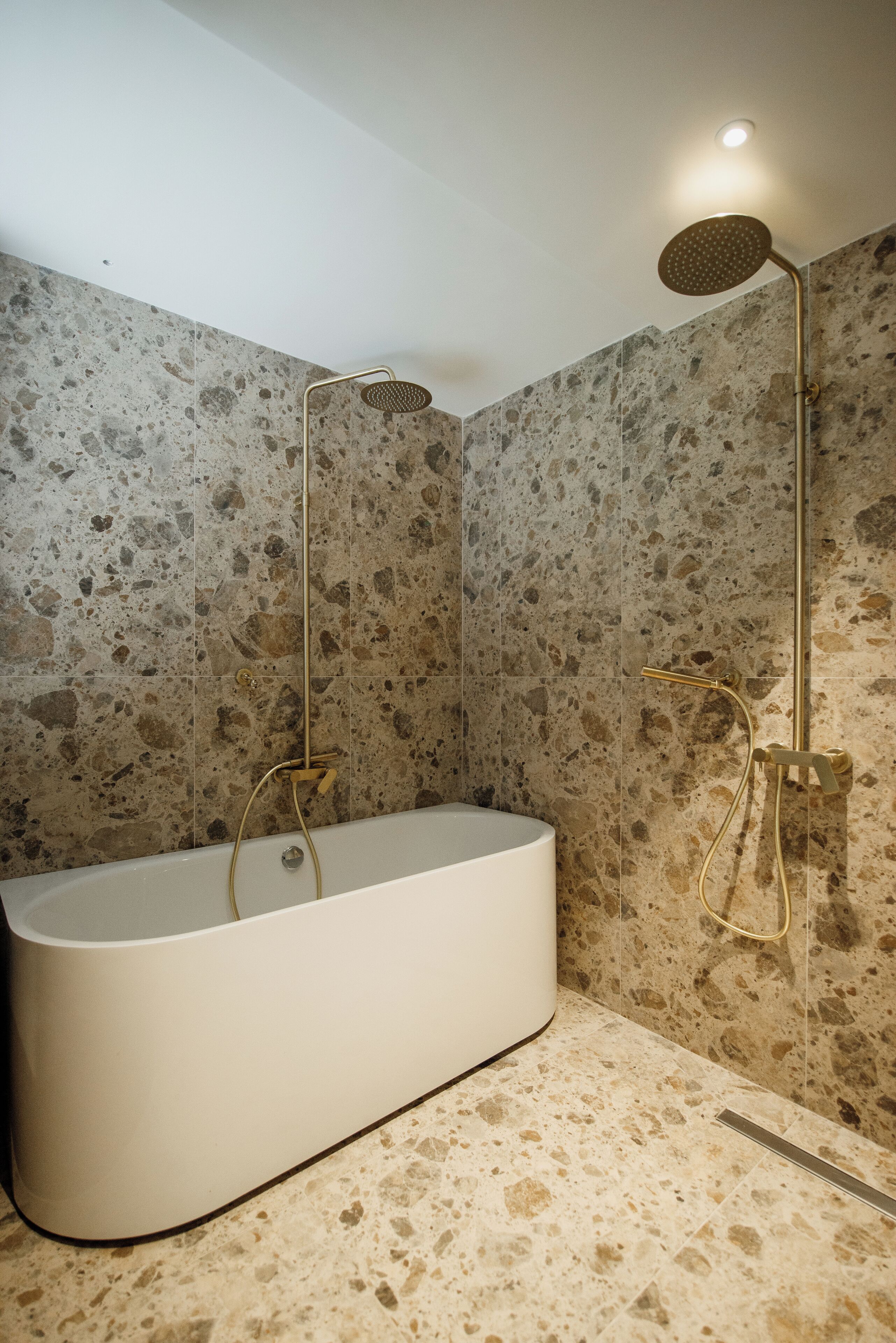 A modern bathroom with a freestanding bathtub, a handheld showerhead, and a wall-mounted showerhead.