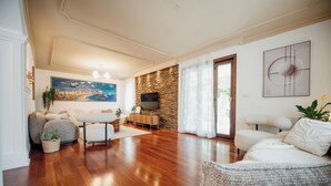 A spacious living room with hardwood flooring, a stone accent wall, a large painting, and a comfortable seating area with sofas and a coffee table. - Villa Danigo (Budva)