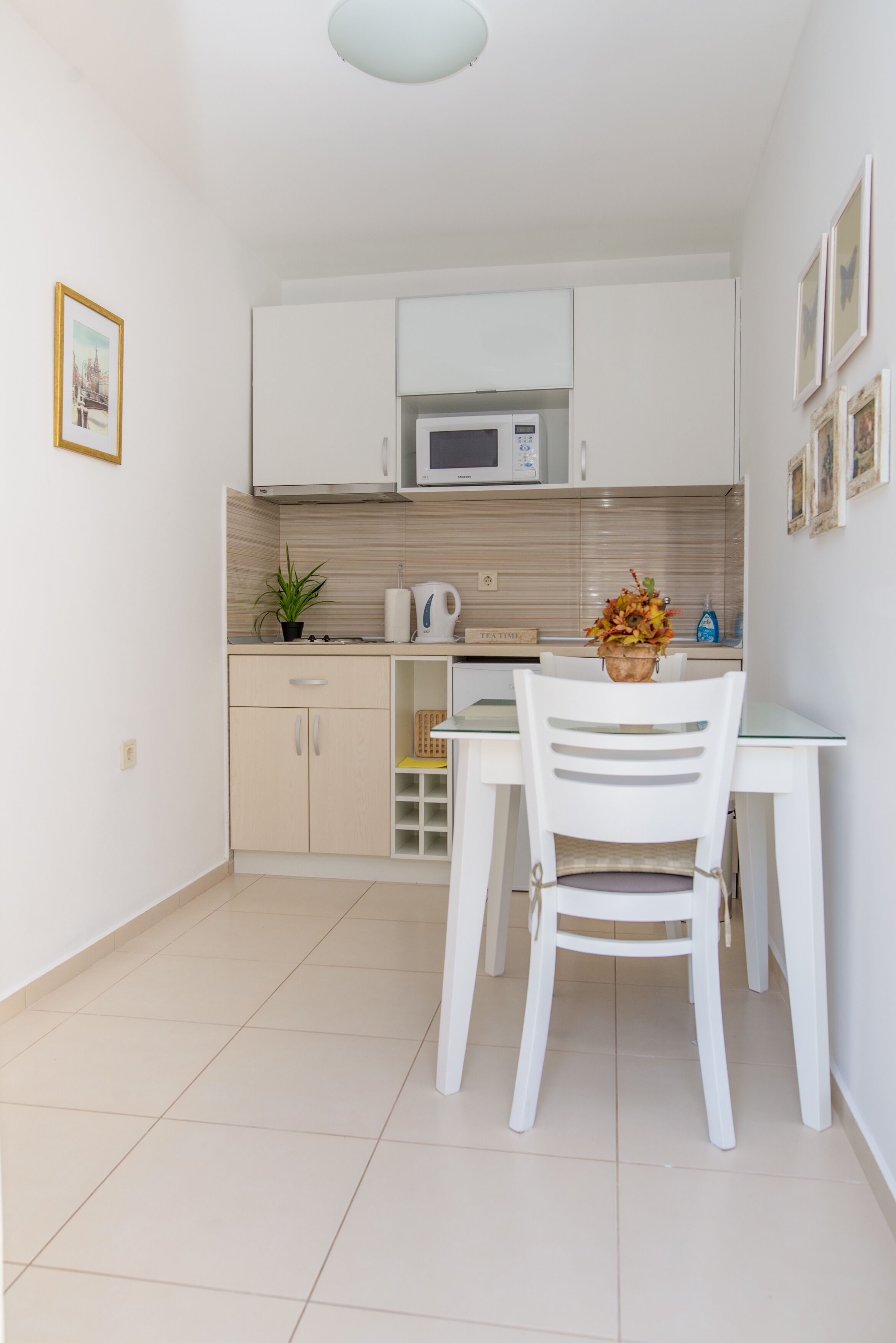 A compact kitchen with white cabinets, a microwave, and a dining table with a chair.