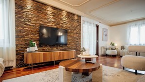 A modern living room with a stone wall, a flat-screen TV, a wooden coffee table, and a sofa. - Villa Danigo (Budva)