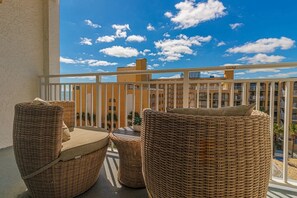 A balcony with wicker furniture and a view of a building with balconies.