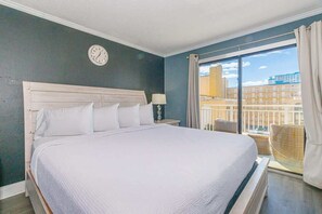 Une chambre d’hôtel avec un lit, une horloge, une fenêtre avec des rideaux et une vue sur des immeubles.