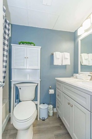Une salle de bain comprenant des toilettes, un lavabo, un meuble et un porte-serviettes.